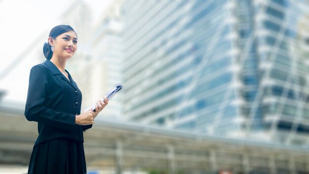 Mulher de negócios asiáticos está com postagem confiável e arquivo de apresentação em espaço público ao ar livre