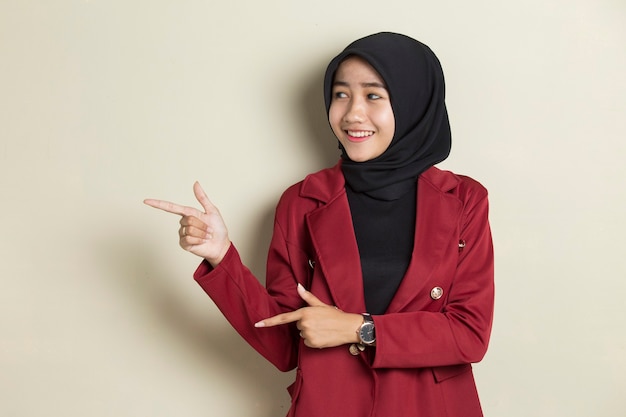 Mulher de negócios asiáticos jovem usando hijab sorrindo confiante apontando com os dedos para diferentes direções.