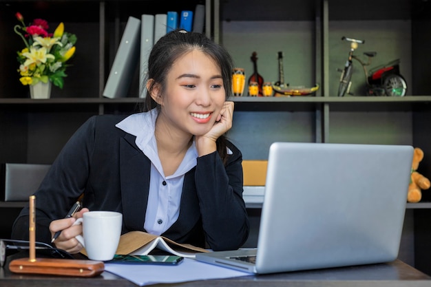 Foto mulher de negócios asiáticos linda casual feliz trabalhando em um laptop no escritório.