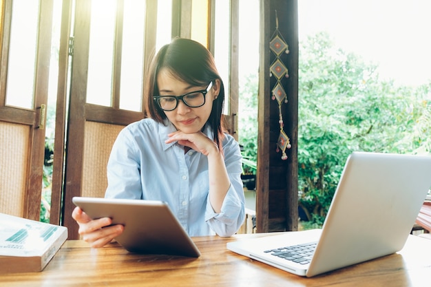 Mulher de negócios asiáticos linda trabalhando com laptop, celular e tablet