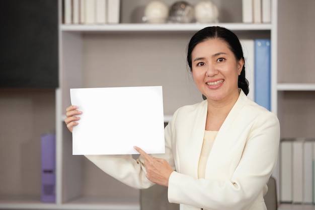 Mulher de negócios asiáticos sorrindo com a mão apontando para o espaço de papel em branco para texto