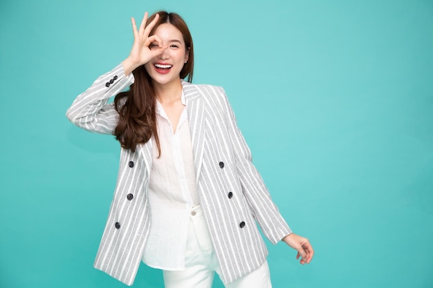 Mulher de negócios asiáticos sorrindo e mostrando sinal de OK isolado sobre fundo verde