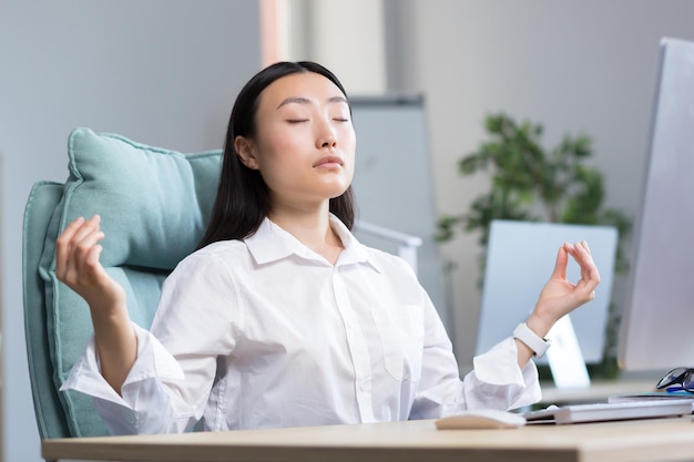 Mulher de negócios asiáticos trabalhando no escritório descansando e meditando fazendo exercícios respiratórios para acalmar