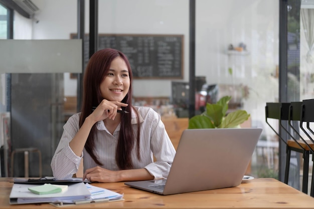 Mulher de negócios asiáticos usando calculadora e laptop para fazer finanças matemáticas em uma mesa de escritório relatório fiscal estatísticas contábeis e conceito de pesquisa analítica