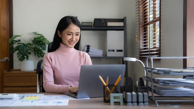 Mulher de negócios asiáticos usando calculadora e laptop para fazer finanças matemáticas em uma mesa de escritório relatório fiscal estatísticas contábeis e conceito de pesquisa analítica