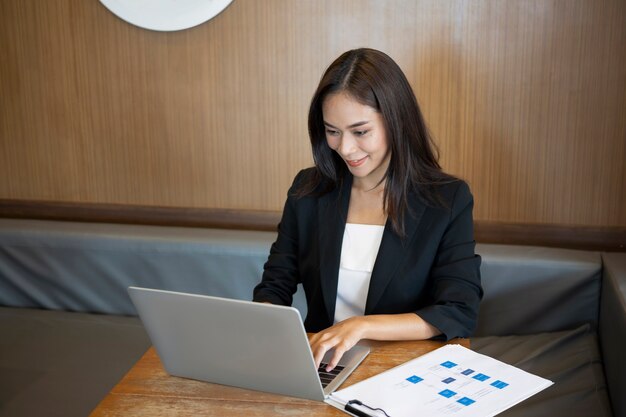 Mulher de negócios atraente em terno trabalhando com laptop no escritório.