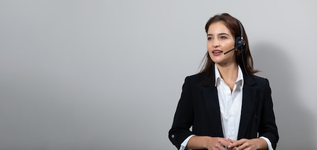 Mulher de negócios atraente em ternos e fones de ouvido sorrindo enquanto trabalhava isolada