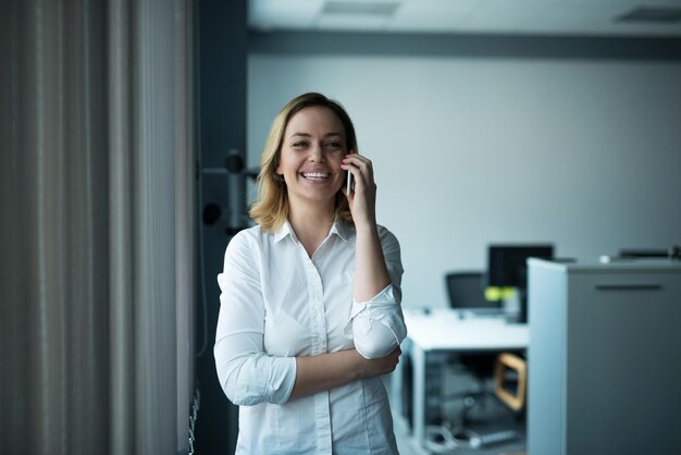 Mulher de negócios atraente falando em um telefone celular em um escritório.