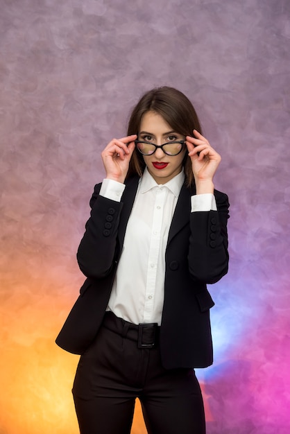 Mulher de negócios atraente gesticulando para uma parede abstrata em óculos originais
