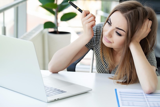 Mulher de negócios atraente trabalhando no laptop em seu local de trabalho.