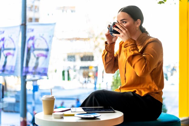 Mulher de negócios bebendo chá vestida de terno em um café