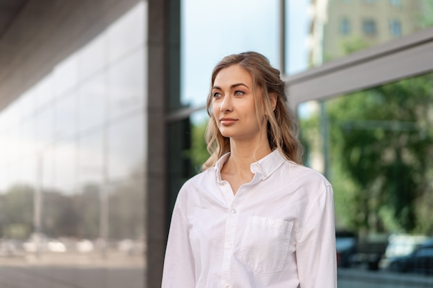 Mulher de negócios bem-sucedida mulher de negócios em pé Exterior de edifício corporativo ao ar livre. Caucasiana Confiança Profissional Mulher de Negócios Meia Idade Feminina Camisa Branca Grande Janela