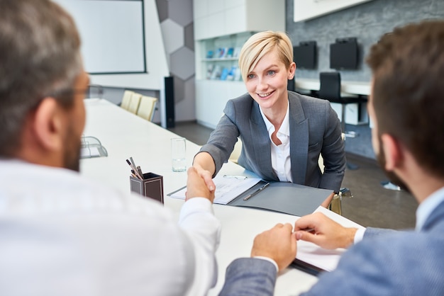 Mulher de negócios bem sucedido Greeting Partners na sala de diretoria