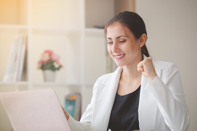 Mulher de negócios bem sucedido procurando laptop com os braços para cima