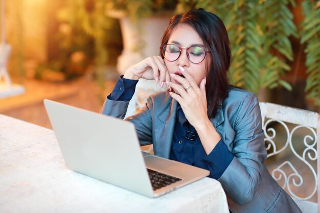 Foto mulher de negócios bocejando enquanto usa laptop na mesa