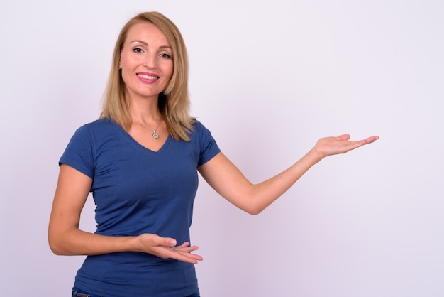 Mulher de negócios bonita com cabelo loiro e camisa azul encostada na parede branca