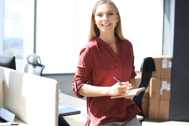 Mulher de negócios bonita está escrevendo algo enquanto está sentado na mesa do escritório.