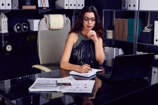 Mulher de negócios bonita jovem trabalhando na mesa preta elegante