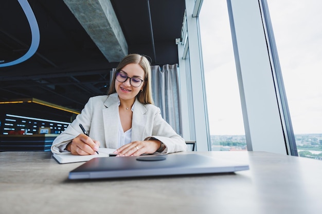 Mulher de negócios bonita olhando através do notebook focado no trabalho freelancer trabalho remoto estudando estudo escritório moderno distanciamento social interno Mulher no escritório com óculos e laptop