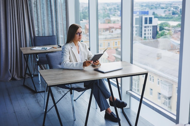 Mulher de negócios bonita olhando através do notebook focado no trabalho freelancer trabalho remoto estudando estudo escritório moderno distanciamento social interno mulher no escritório com óculos e laptop