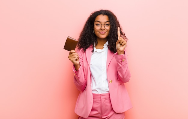 Mulher de negócios bonita preta jovem com uma carteira contra parede rosa