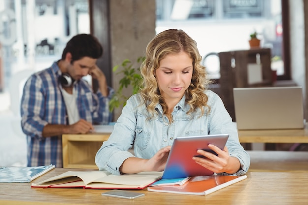 Mulher de negócios bonita que usa a tabela no escritório