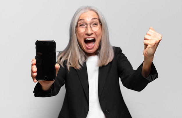 Mulher de negócios bonita sênior com um telefone inteligente.