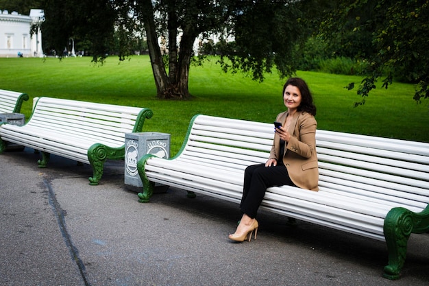 Mulher de negócios bonita sentada no parque em um banco