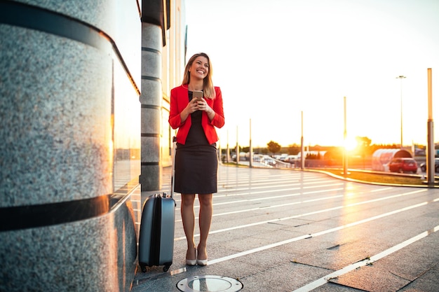 Mulher de negócios bonita usando telefone celular em pé em um aeroporto