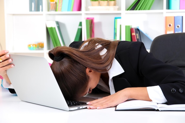 Mulher de negócios cansada com notebook em seu local de trabalho