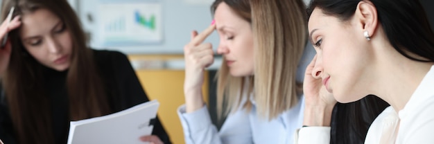 Mulher de negócios cansada e pensativa com documentos e laptops em sua mesa de trabalho. conceito de metas e tarefas de negócios desafiadoras