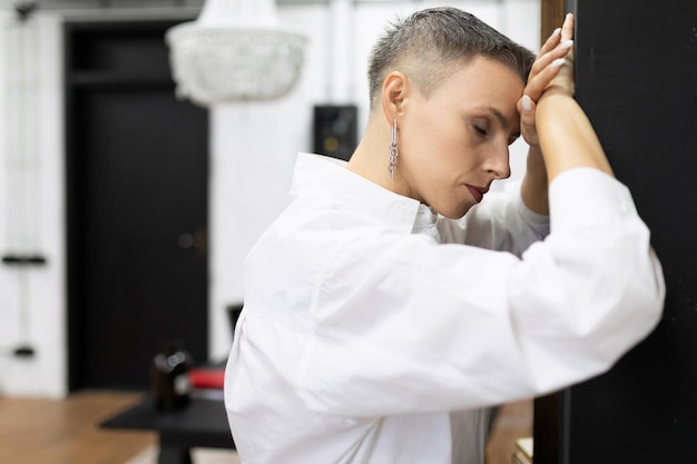 Mulher de negócios cansada encostada na parede com os olhos fechados descansando