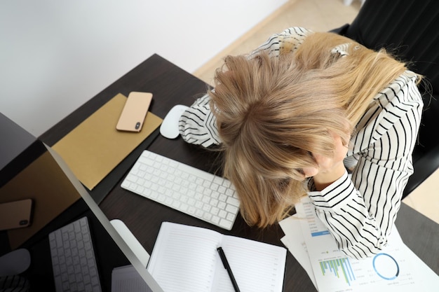Foto mulher de negócios cansado jovem sentado no local de trabalho