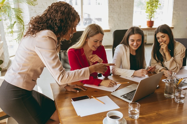 Foto mulher de negócios caucasiana jovem em um escritório moderno com a equipe. reunião criativa, atribuição de tarefas. mulheres trabalhando no escritório. conceito de finanças, negócios, poder feminino, inclusão, diversidade, feminismo.