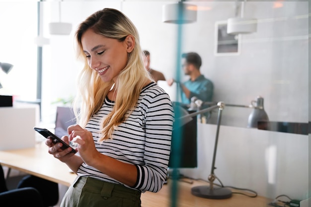 Mulher de negócios caucasiana sorridente assistindo no smartphone durante o trabalho no escritório