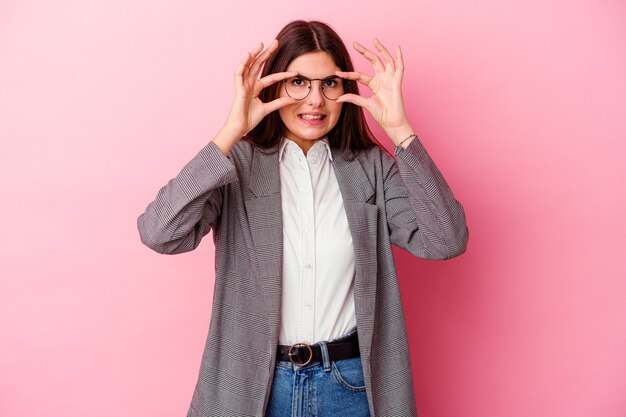 Mulher de negócios caucasiano jovem isolada na parede rosa, mantendo os olhos abertos para encontrar uma oportunidade de sucesso.