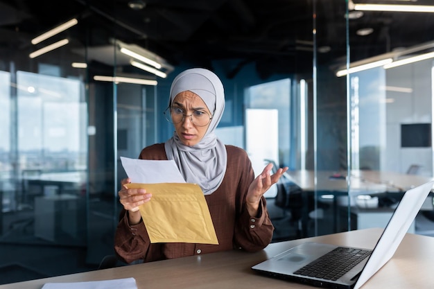 Mulher de negócios chateada em hijab trabalhando dentro do escritório mulher recebeu correio de envelope de carta com mau