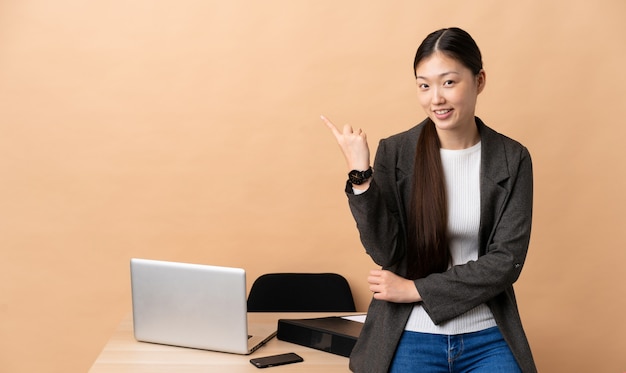 Mulher de negócios chinês em seu local de trabalho, apontando o dedo para o lado