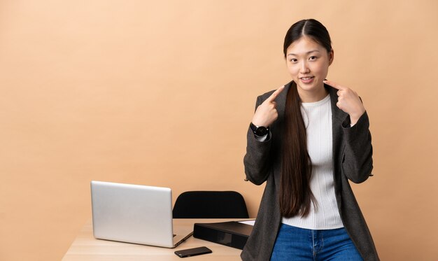 Mulher de negócios chinês em seu local de trabalho, dando um polegar para cima gesto