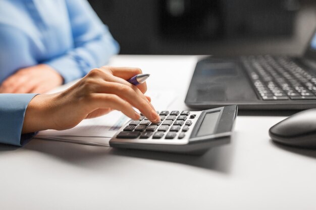 Mulher de negócios com calculadora no escritório noturno.