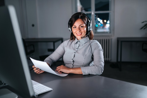 Mulher de negócios com fone de ouvido trabalhando à noite.