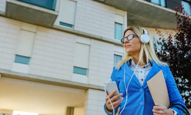 Mulher de negócios com fones de ouvido e celular na rua