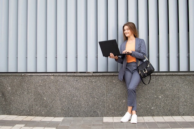 Mulher de negócios com laptop contra uma parede