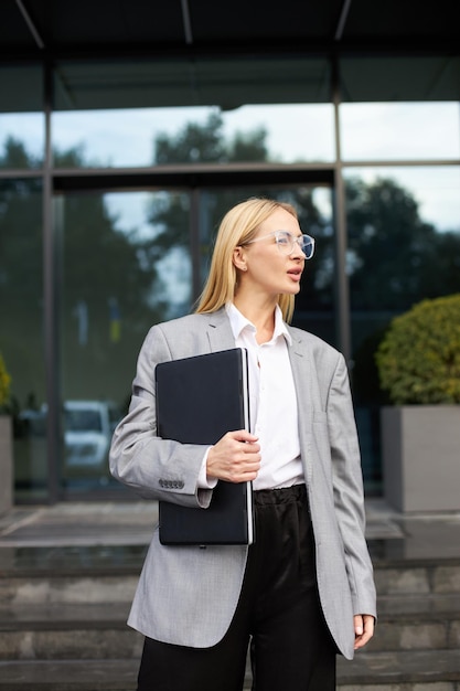 Mulher de negócios com laptop vestido de terno formal em pé ao ar livre