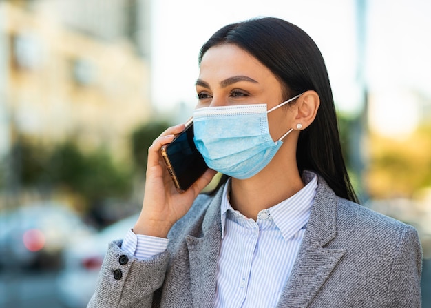 Mulher de negócios com máscara médica falando ao telefone