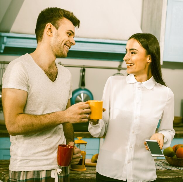 Mulher de negócios com o marido de pijama ri da cozinha