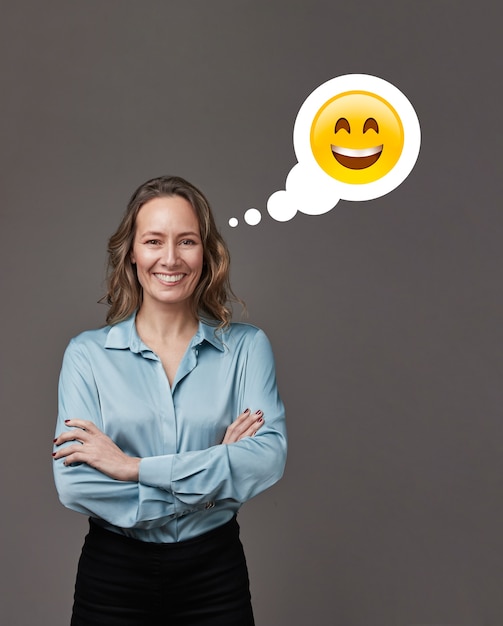 Foto mulher de negócios com os braços cruzados em cinza pensando com uma cara feliz.