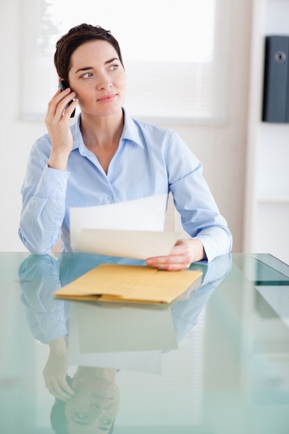 Mulher de negócios com papéis no telefone