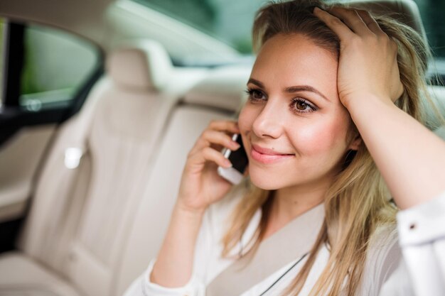 Mulher de negócios com smartphone sentada nos assentos traseiros de um táxi