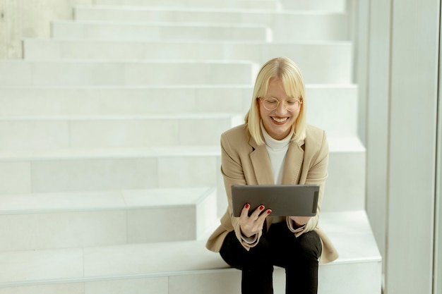 Mulher de negócios com tablet digital nas escadas do escritório moderno